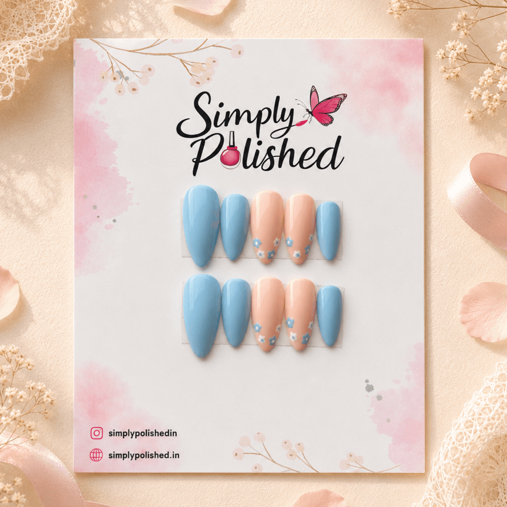 Handcrafted press-on nails with delicate blue floral art on a soft nude base.