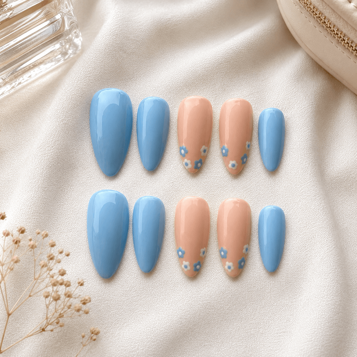 Handcrafted press-on nails with delicate blue floral art on a soft nude base.